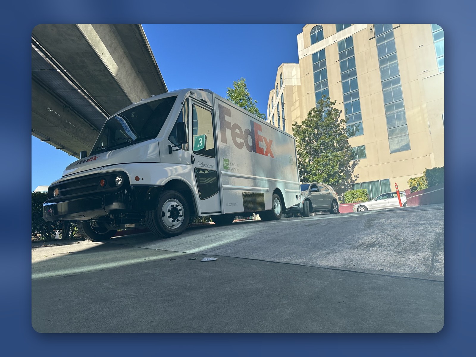 A Workhorse W56 electric step van pulling into a FedEx facility under an overpass.