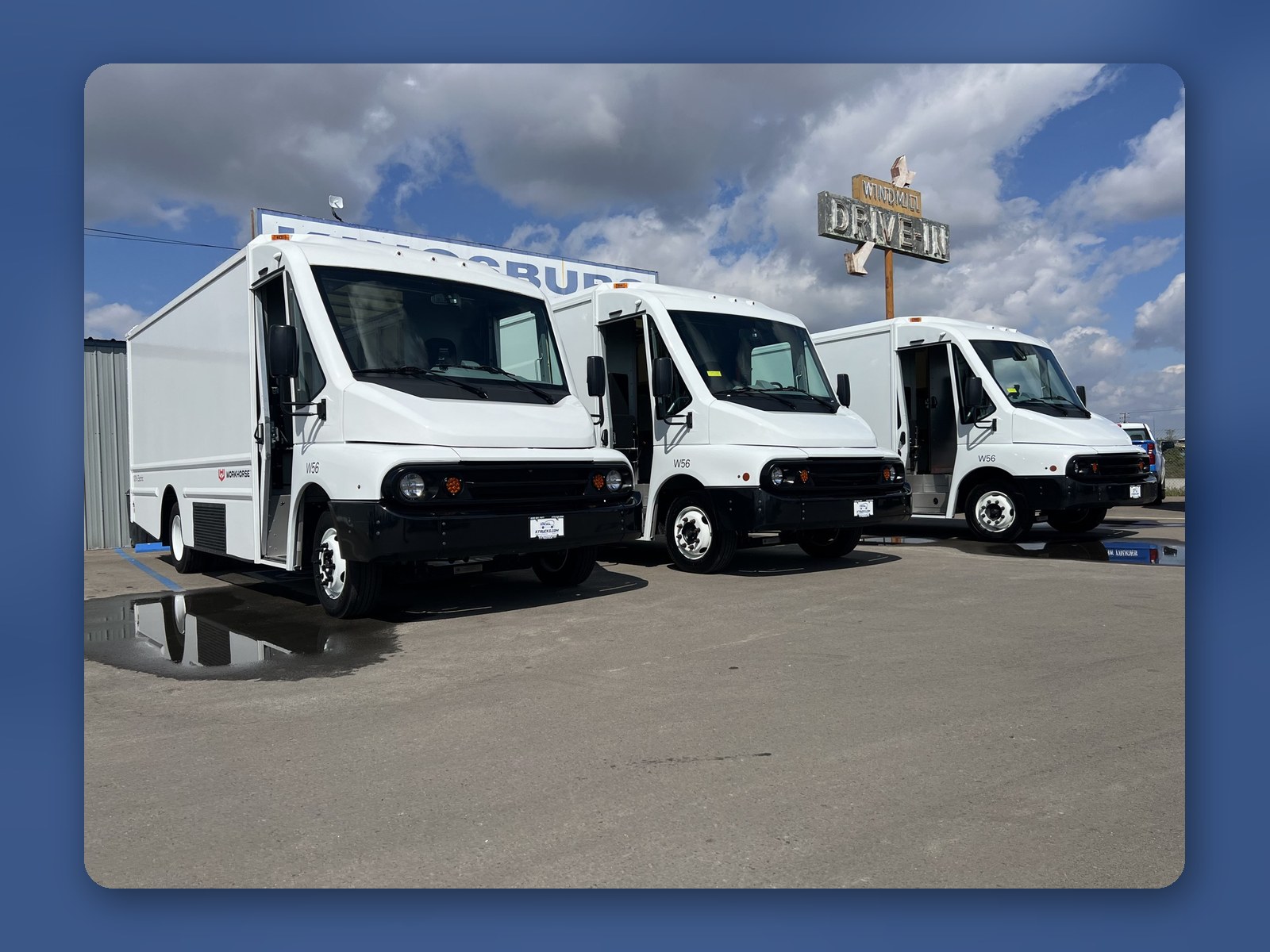 A row of new white Workhorse W56 step vans lined up outside on an overcast day.