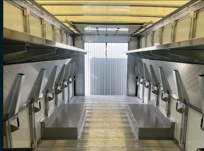 Package C Fixed Top / Folding Bottom shelving in a Workhorse W56 step van, lower folding shelves raised against the wall with the roll-up door open.