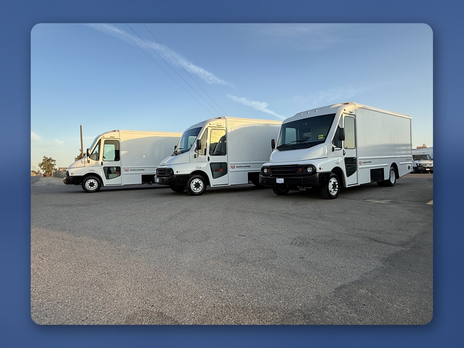 Three white Workhorse W56 step vans staged outside under a clear blue sky.